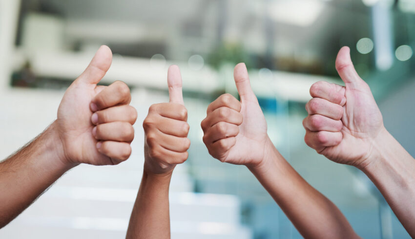 Cropped shot of a group of hands showing thumbs up in an office.