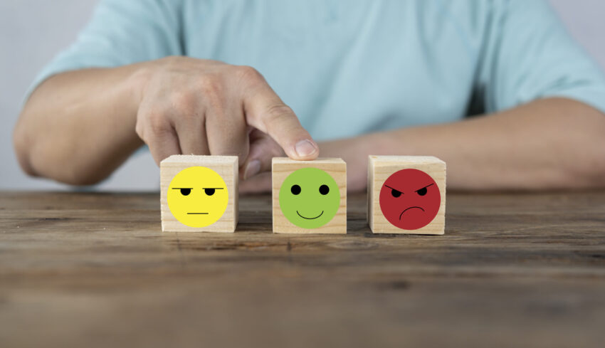 Hand choosing happy smile face wooden block, good feedback rating and positive customer review, mental health assessment, child wellness,world mental health day,think positive, emotional scale concept